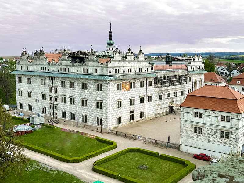 a large white building with a lawn and a car parked in front of it. Litomysl castle.